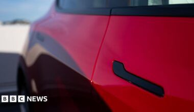 A black door handle on a red Tesla Model Y at a charging station in San Francisco, California, US.