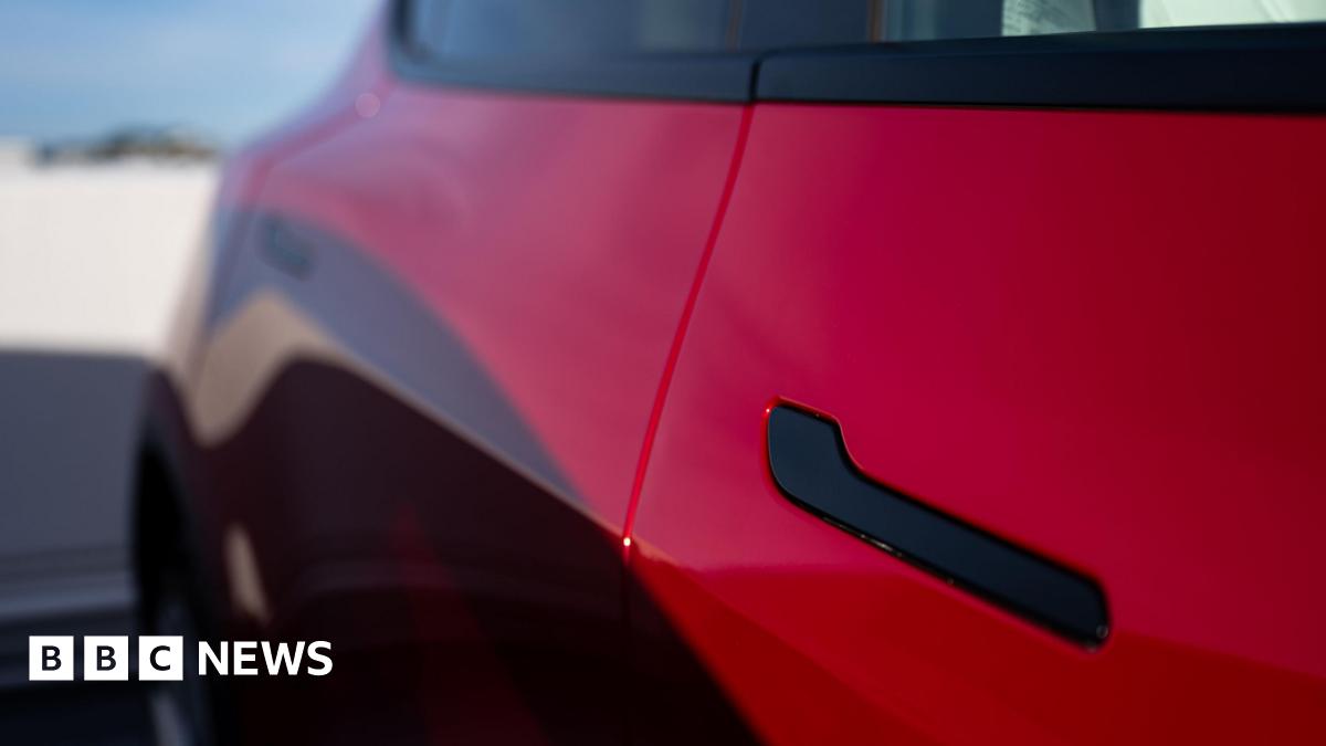 A black door handle on a red Tesla Model Y at a charging station in San Francisco, California, US.