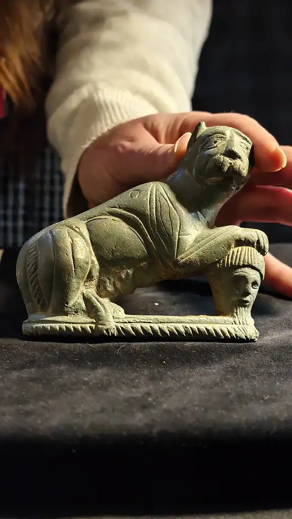 Ancient stone lion sculpture held by a person for display.