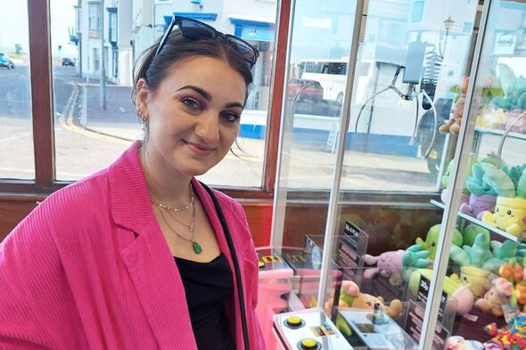 woman in pink coat at amusements near sea
