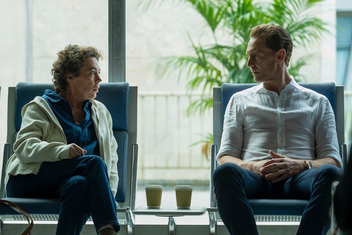 Olivia Colman and Tom Hiddleston star in The Night Manager season 2; in this scene, Angela and Pine are sat next to each other in an airport waiting area, having a serious conversation