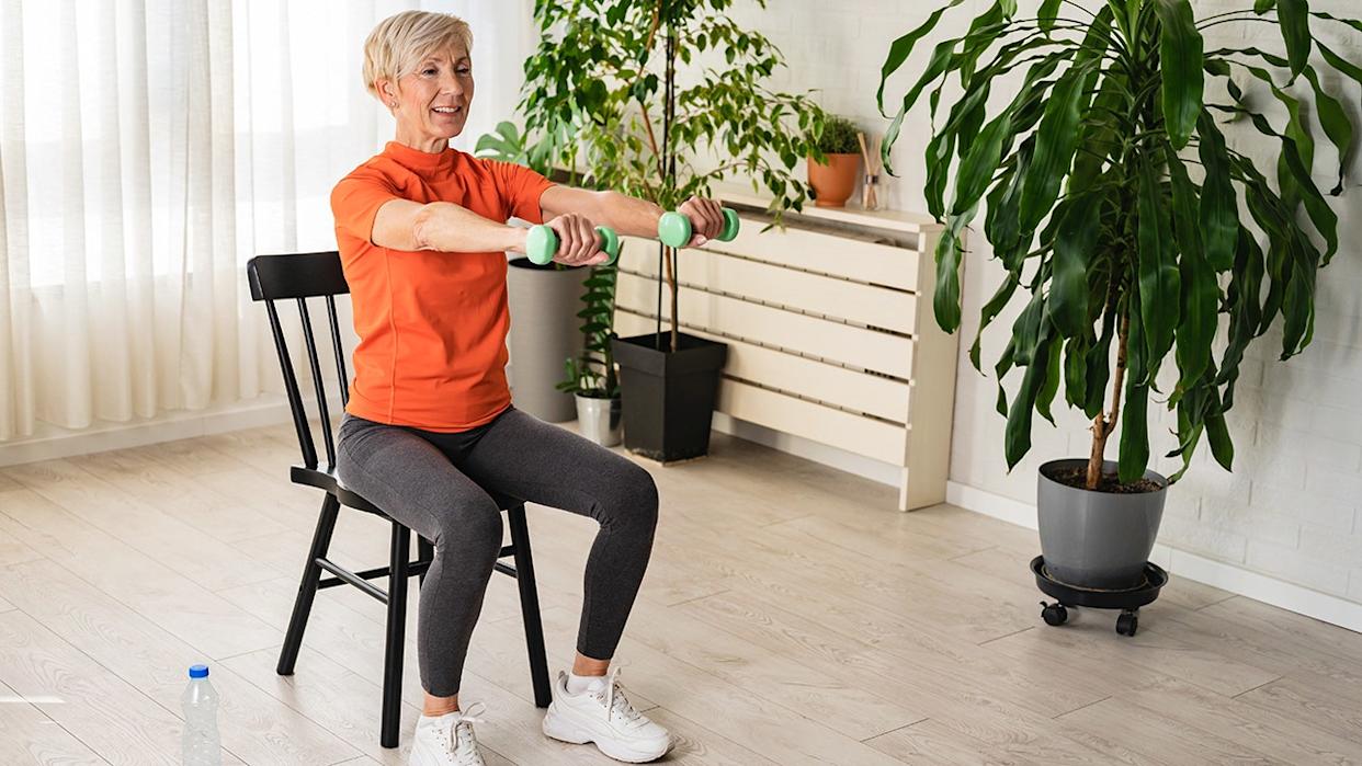 senior woman health instructor doing chair exercises with dumbbells