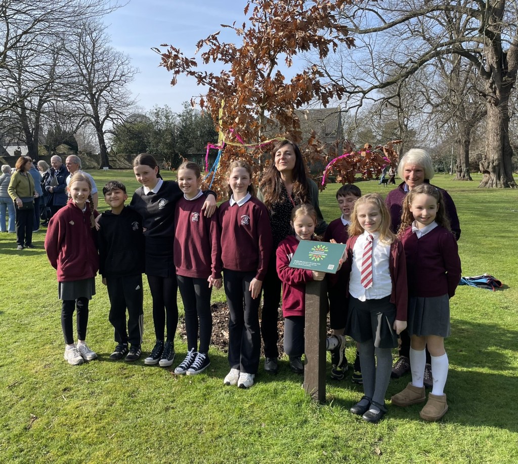 An image of a group of Cramond Primary schoolchildren with the oak tree they planted four years ago.