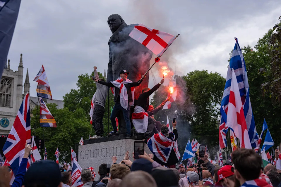People sit on the Churchill statue with flares as they take part in the 
