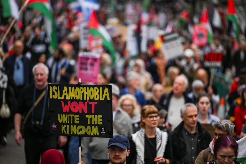 Protesters march, one holds a flag saying 'Islamaphobia won't unite the Kingdom'.