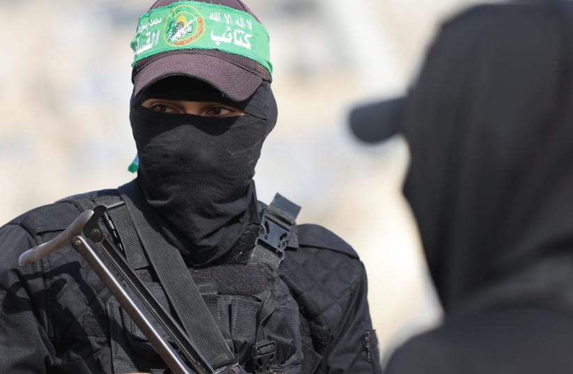 Hamas members look on as they escort members of the Red Cross towards an area within the yellow line, in Gaza City, November 12, 2025.