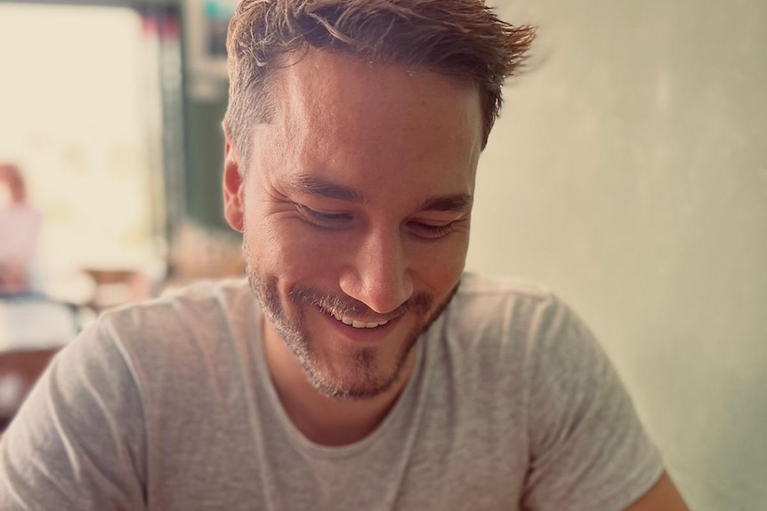 Darcy Mangan smiles, looking down at his phone