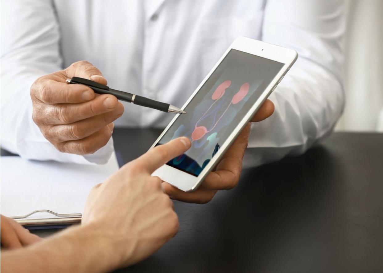 Urologist with tablet computer speaking with patient. -