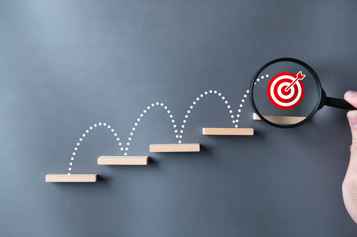A bullseye jumping up stairs with a magnifying glass on it.