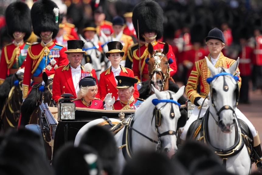 The king and queen in a horse drawn carriage followed by British footguards in bearskin hats.