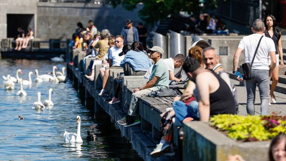 Visitors sit on the bank of a lake in hot weather in Zurich, Switzerland, on Friday, May 22. Switzerland will vote on the initiative to cap the population at 10 million on June 14. - Stefan Wermuth/Bloomberg/Getty Images