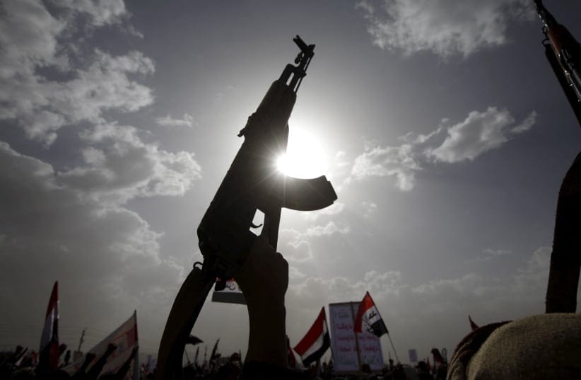 A Houthi follower rises a weapon as he attends a rally marking one year of Saudi-led air strikes, in Yemen's capital Sanaa.