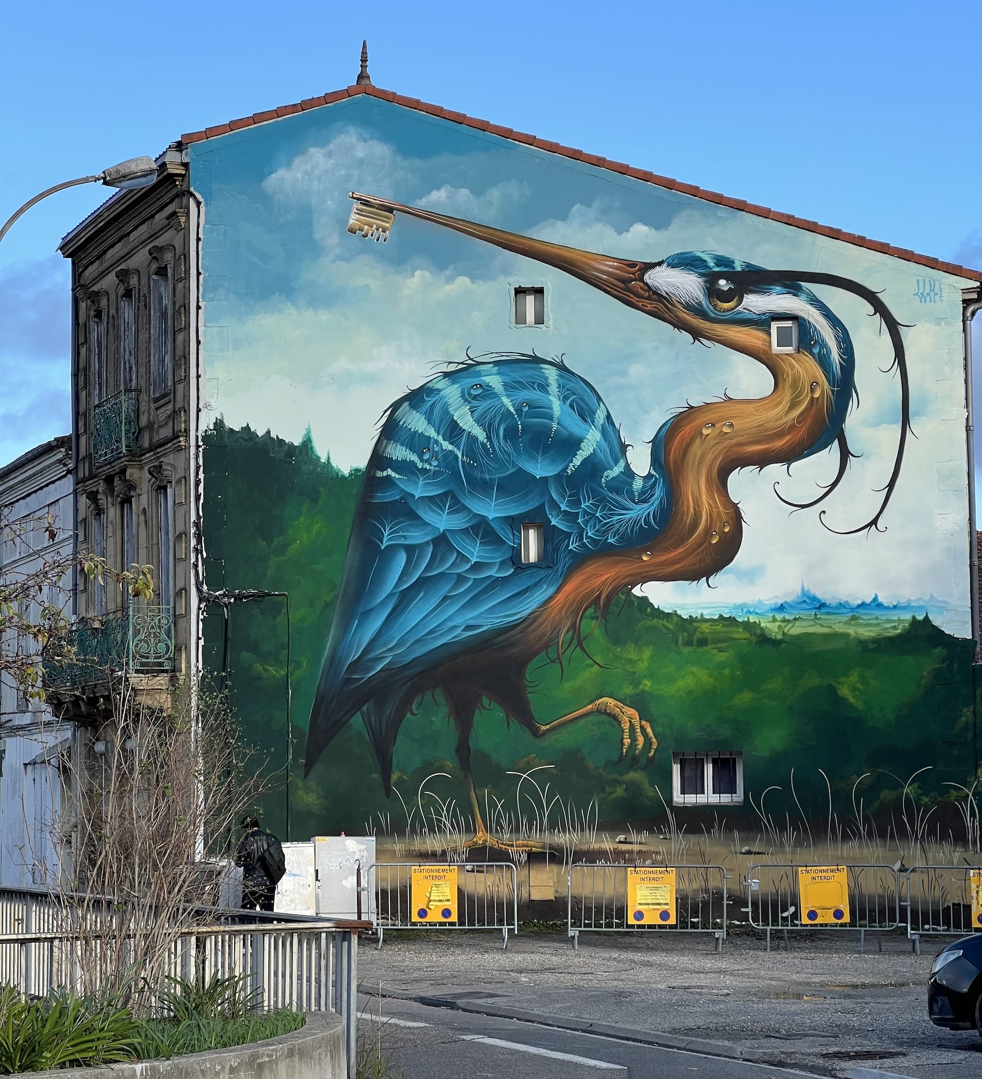 a mural on the side of a residential building of a large heron-like bird with a beak that turns into a large key