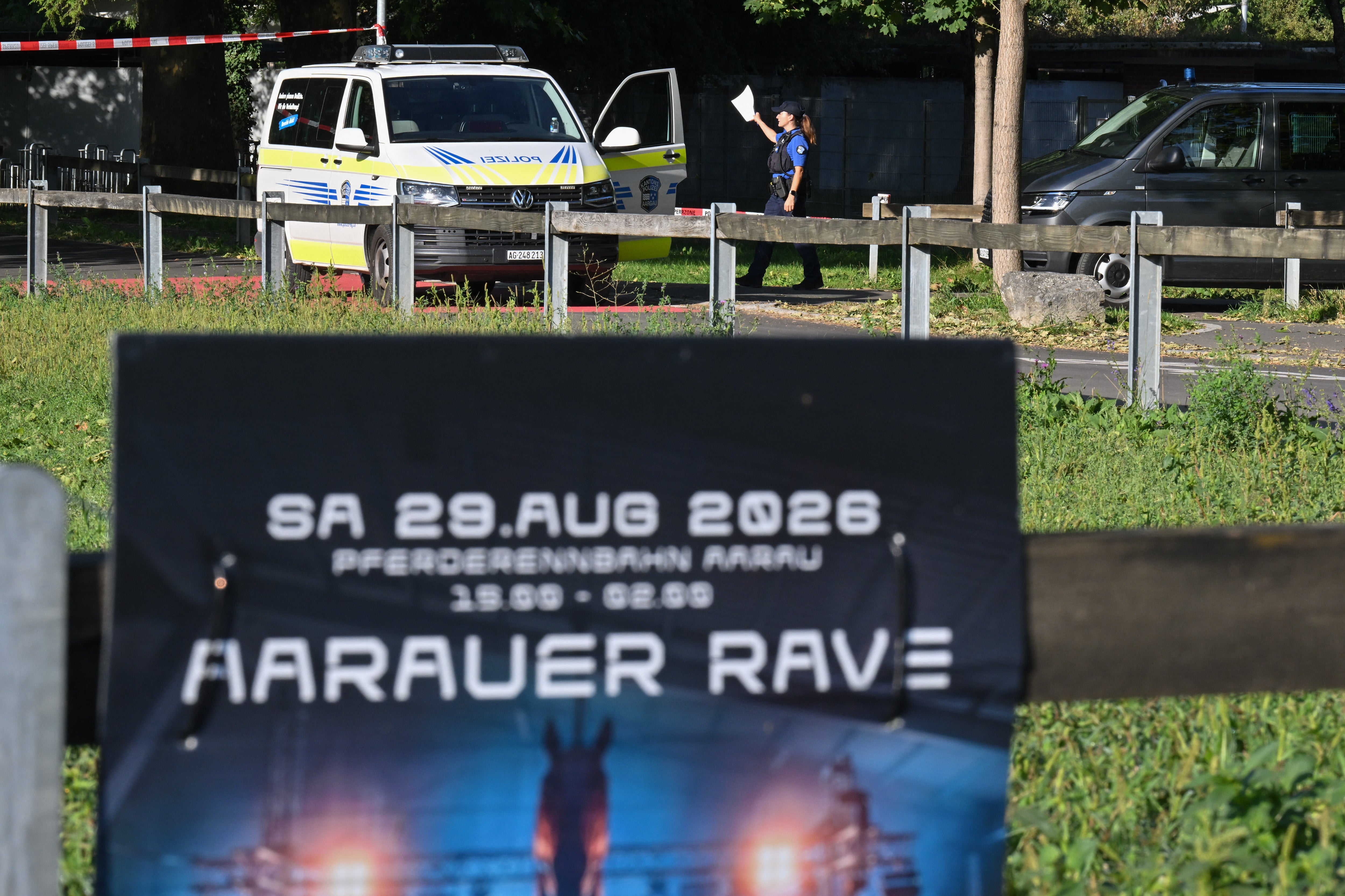 Police officers secure the area behind a poster advertising a rave where a shooting occurred, in Aarau, northern