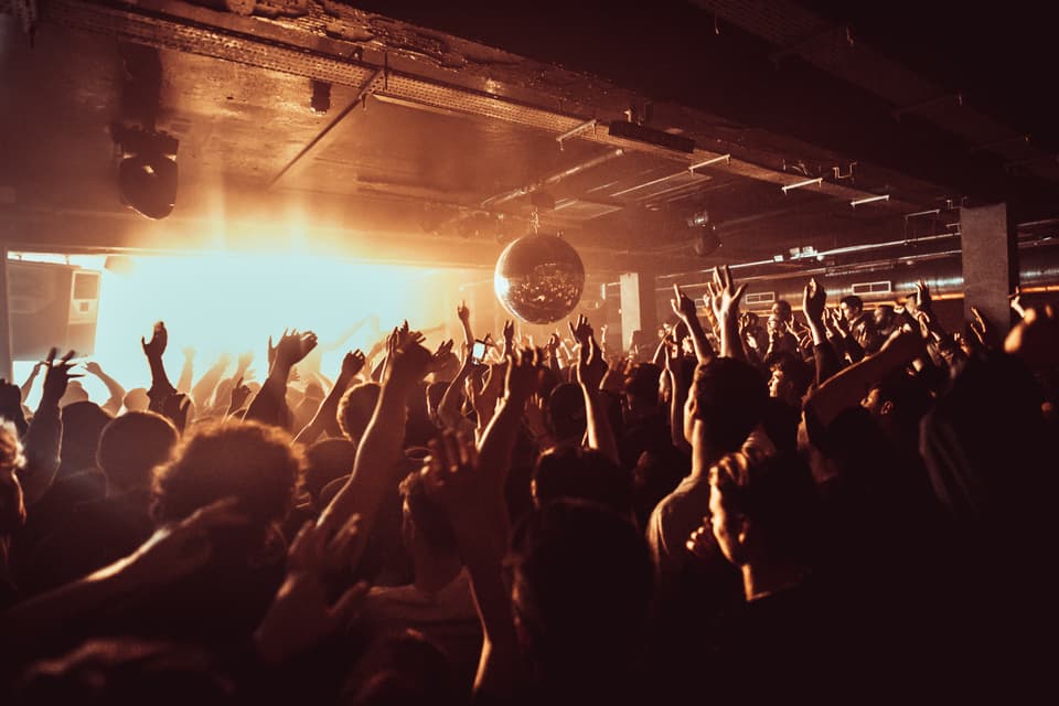 People dance with arms in the air at Phonox nightclub