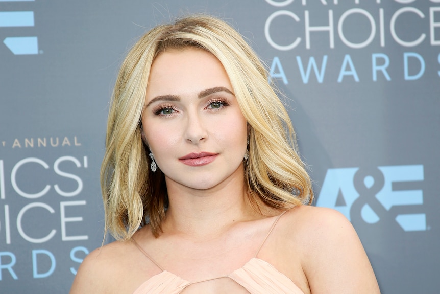 Hayden Panettiere wears a peach halter-neck dress and her blonde hair loose down to her shoulders.