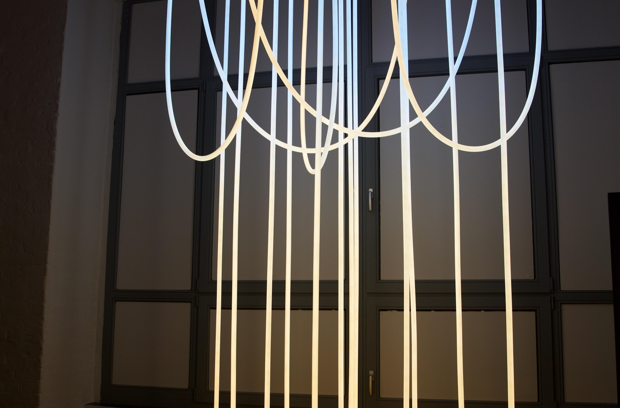 Philips Hue’s new glowing Liane rope lights suspended from the ceiling in a room.