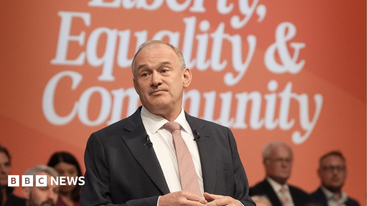 Sir Ed Davey at the Liberal Democrat party conference. He is pictured against a blue and red background, and he is gesturing with his hands as he makes his speech.