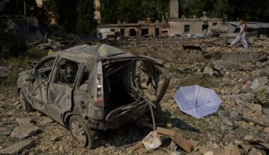 A local resident walks past destroyed vehicles and scattered debris the day after a Russian missile and drone attack in Kyiv, on Aug. 21, 2026.