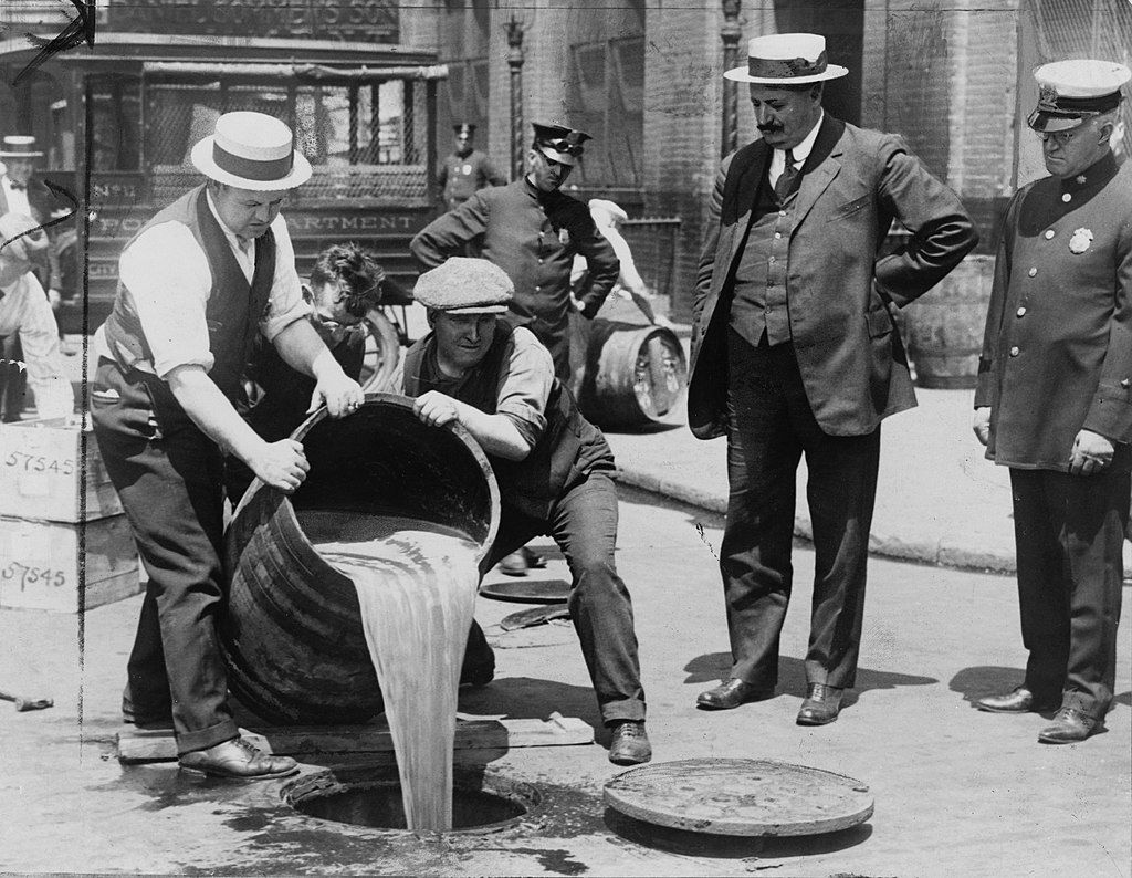 New York City Deputy Police Commissioner John A. Leach, right, watching agents pour liquor into sewer following a raid during the height of prohibition