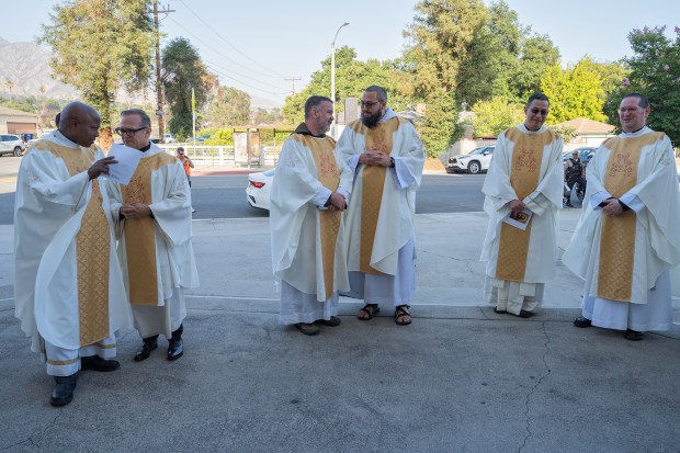 A group of priests gathers in front of Sacred Heart...