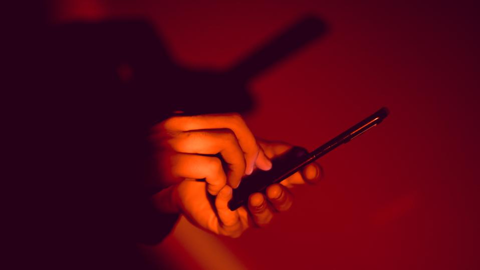 Person using smartphone in dark room with red light