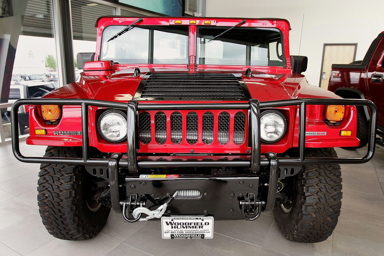 An older red hummer in a dealership.
