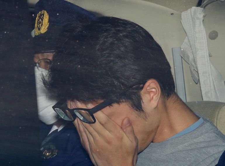 Takahiro Shiraishi covers his face inside a police car in Tokyo, in this photo taken by Kyodo November 2017 and released by Kyodo December 15, 2020. Mandatory credit Kyodo/via REUTERS ATTENTION EDITORS - THIS IMAGE WAS PROVIDED BY A THIRD PARTY. MANDATORY CREDIT. JAPAN OUT.