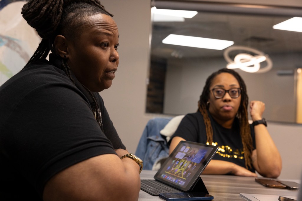 Two Black women sit at a conference table