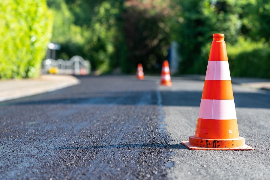 A construction cone marking part of a road with a layer of fresh asphalt.