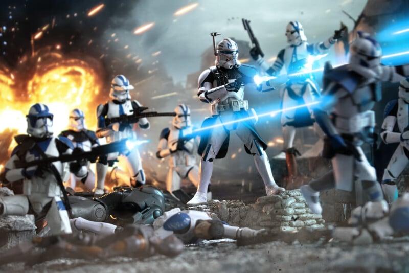 Clone troopers in white and blue armor fire blasters in a dramatic battle scene, with explosions in the background and fallen droids on the ground, evoking intense combat from the Star Wars universe.