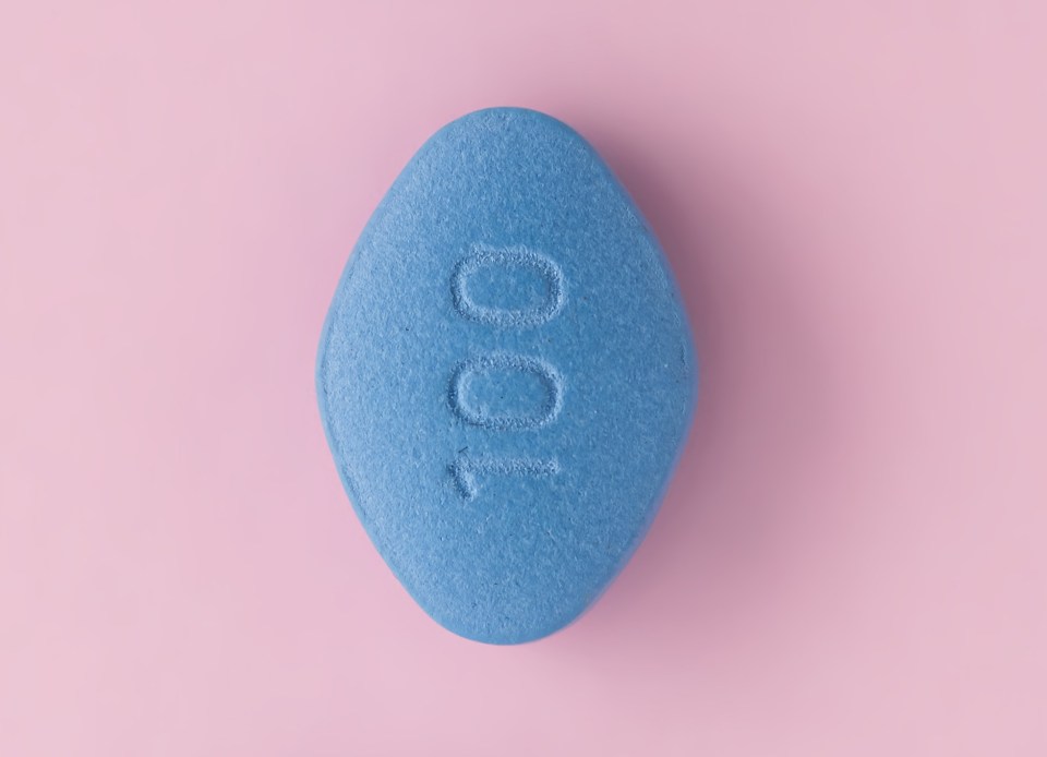 Three blue pills on a pink background.