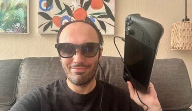 A selfie of the author wearing XREAL Air 2 AR glasses tethered to a Steam Deck held in his left hand next to his face.