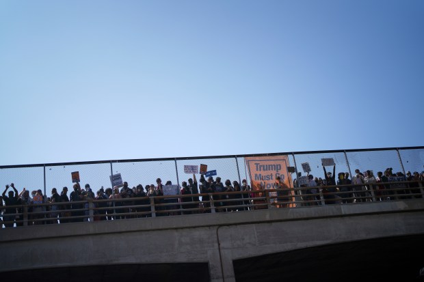 Protesters are seen on an overpass over the 101 Freeway...