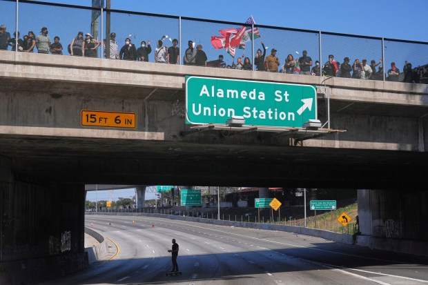 A man skateboards on the 101 Freeway as protesters are...