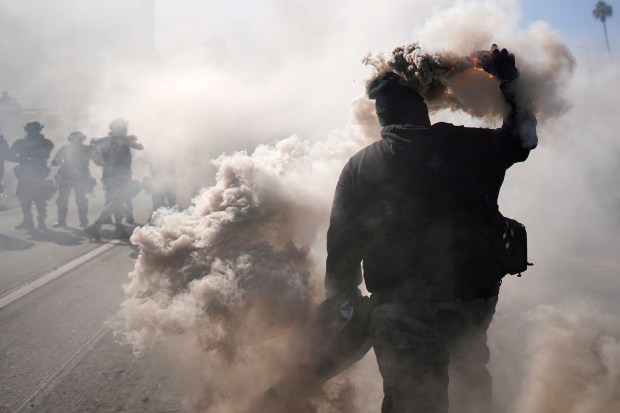 A protester throws a smoke canister on the 101 Freeway...