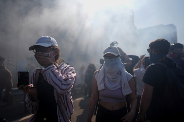 Protesters are seen through smoke on the 101 Freeway near...