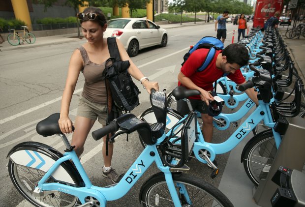 While visiting Chicago from Argentina, Cecilia Reta and her boyfriend Ezequiel Borra rent bikes at the Divvy bike share station at Illinois Street and McClurg Court on June 28, 2013. (Terrence Antonio James/Chicago Tribune)