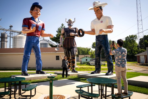 Eric Wagner, with the state tourism office, photographs Ding Peng, from China, with giant "muffler man" fiberglass statues collected at the American Giants museum in Atlanta, Illinois, June 21, 2025. (E. Jason Wambsgans/Chicago Tribune)