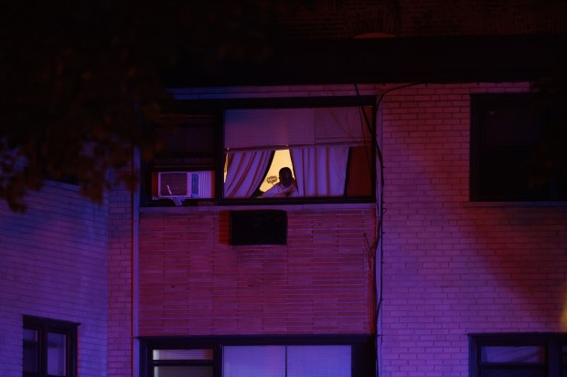 A person in a window watches as police work the...