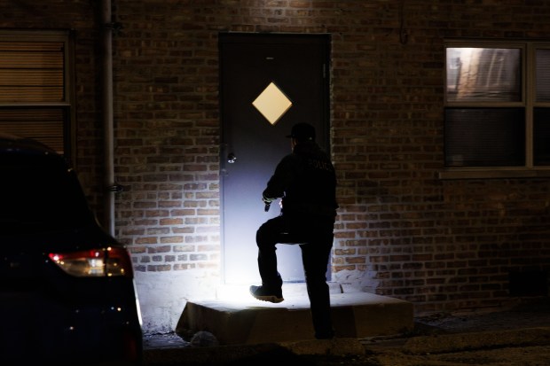 Police search a residential building at the scene where Officer...