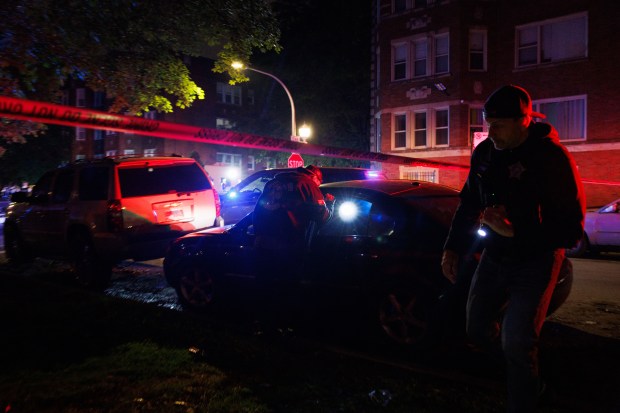 Police look through a vehicle at the scene where Officer...