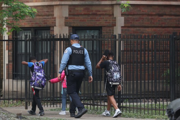 A police officer walks past children as detectives investigate the...