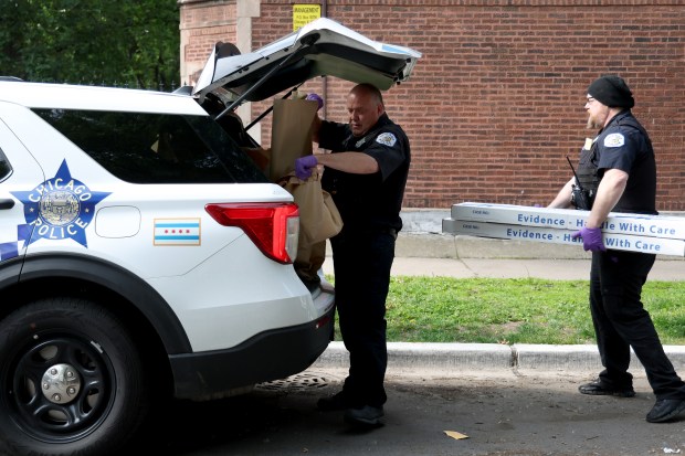 Chicago police carry evidence bags as they finish up investigating...