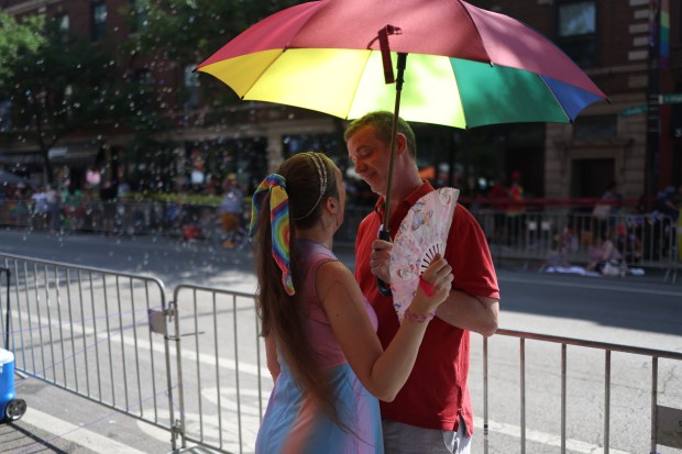 Jamie Brouillette, left, and Thom Holtquist cool off along Broadway Street before the 54th annual Chicago Pride Parade on June 29, 2025. (Audrey Richardson/Chicago Tribune)