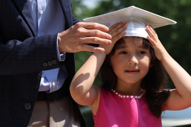Camerino Gomez places a mortar on Gabriela Pineda's head as they get ready for a photo after her kindergarten graduation on June 11, 2025. (Antonio Perez/Chicago Tribune)