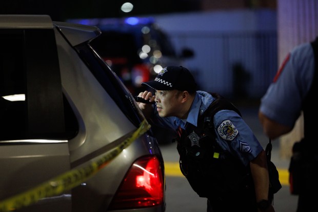A Chicago police officer looks inside a van where a 4-year-old boy was shot in the back while traveling on the 3100 block of South Ashland before he was driven to the University of Illinois Hospital, May 14, 2025. (Armando L. Sanchez/Chicago Tribune)