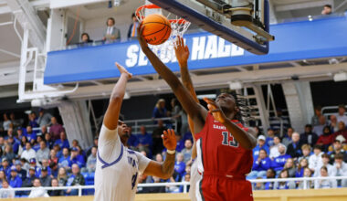 Rasheer Fleming #13 of the Saint Joseph's Hawks puts up a shot against Elijah Hutchins-Everett #4 a...