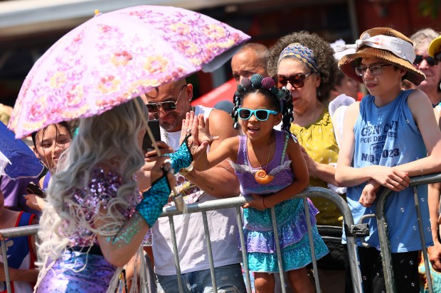 NEW YORK, NEW YORK - JUNE 21: A person in a mermaid costume high fives a young girl as she participates in the 43rd annual Mermaid Parade at Coney Island on June 21, 2025 in New York City. The annual Mermaid Parade marks the beginning of summer in NYC and pays tribute to Coney Island's Mardi Gras celebrations in the early 1900's. (Photo by Michael M. Santiago/Getty Images)