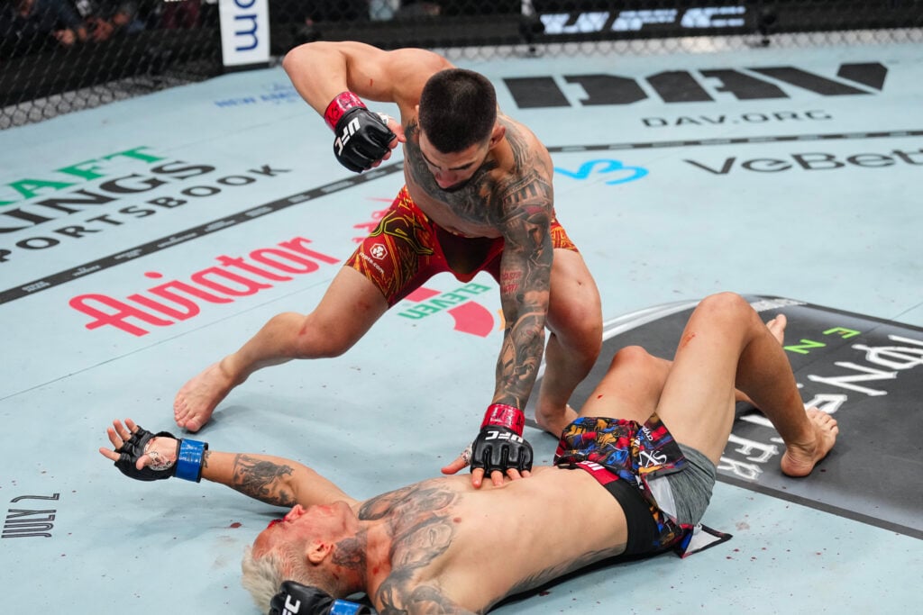 Ilia Topuria punches Charles Oliveira after knocking him out at UFC 317